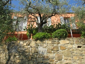 Eine Steinsäule mit einem Baum vor einem Gebäude mit roten und weißen Wänden.