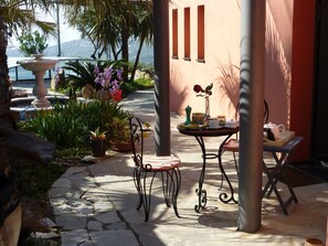 Eine Terrasses mit Tisch, Stühlen und verschiedenen Blumentöpfen.