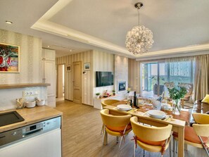 A modern kitchen with a Bosch dishwasher, a dining area with yellow chairs, a chandelier, and a large window with a view. - Villa in Fazana With Swimming Pool (Fazana)