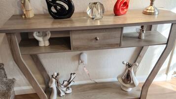A wooden desk with decorative items and a lamp.