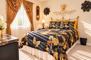 A bedroom with a bed, curtains, a nightstand, a lamp, and wall decorations.