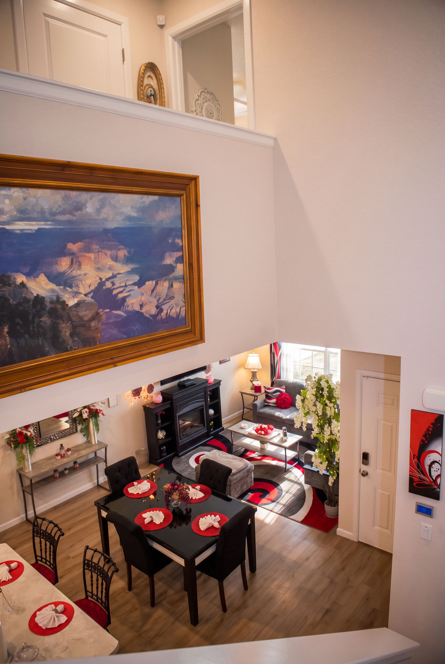 A dining area with a large painting, a table set for four, and a view of a staircase leading to another room.