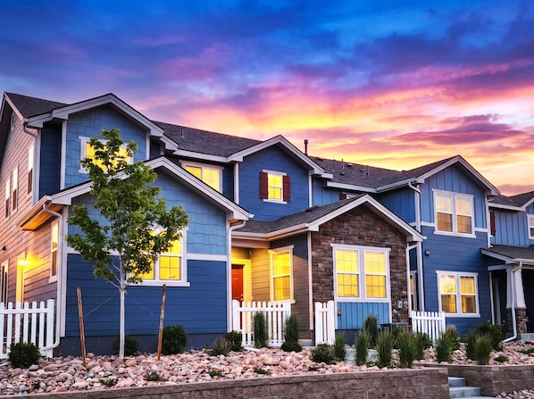 A row of blue houses with white railings and a sunset sky.