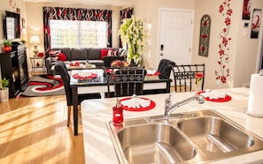 A modern kitchen with a stainless steel sink, a dining table with red placemats, and a black and red patterned window treatment. - 3-bedroom luxury townhome in charming Colorado Springs w/AC - Paradise Point (Colorado Springs)