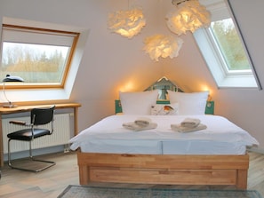 A bedroom with a wooden bed, a desk with a chair, and a skylight. - To the W9 Lighthouse Prerow (Ostseebad Prerow)