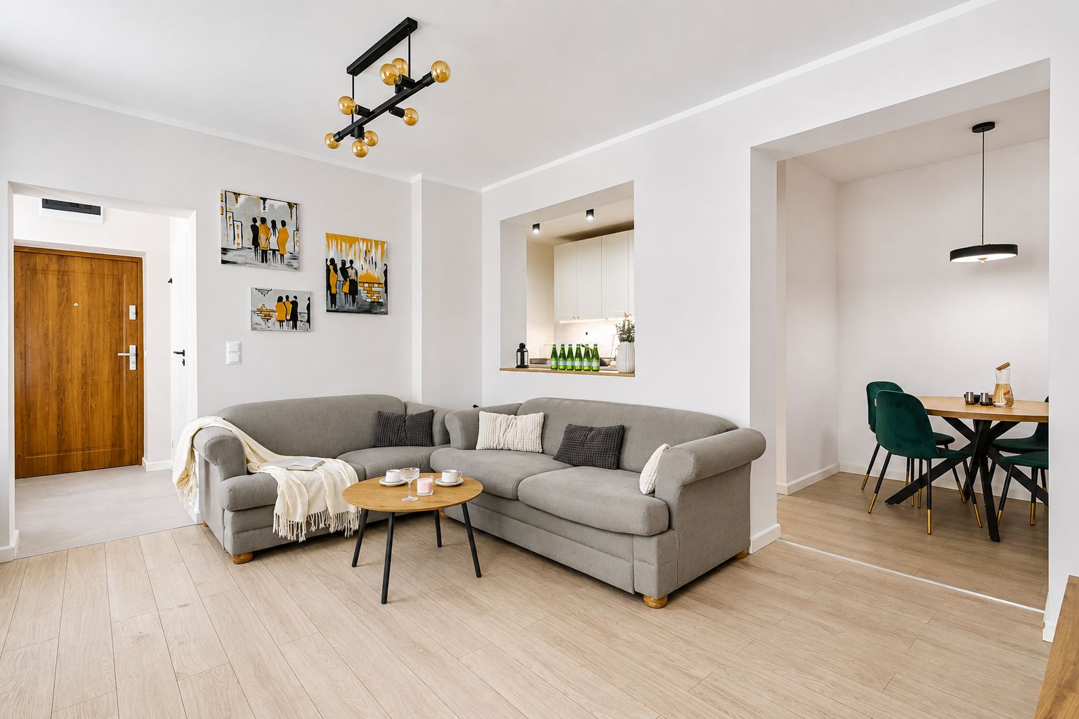 Una sala de estar moderna con un sofá seccional gris, una mesa de centro de madera y un comedor con una mesa de madera y sillas verdes.