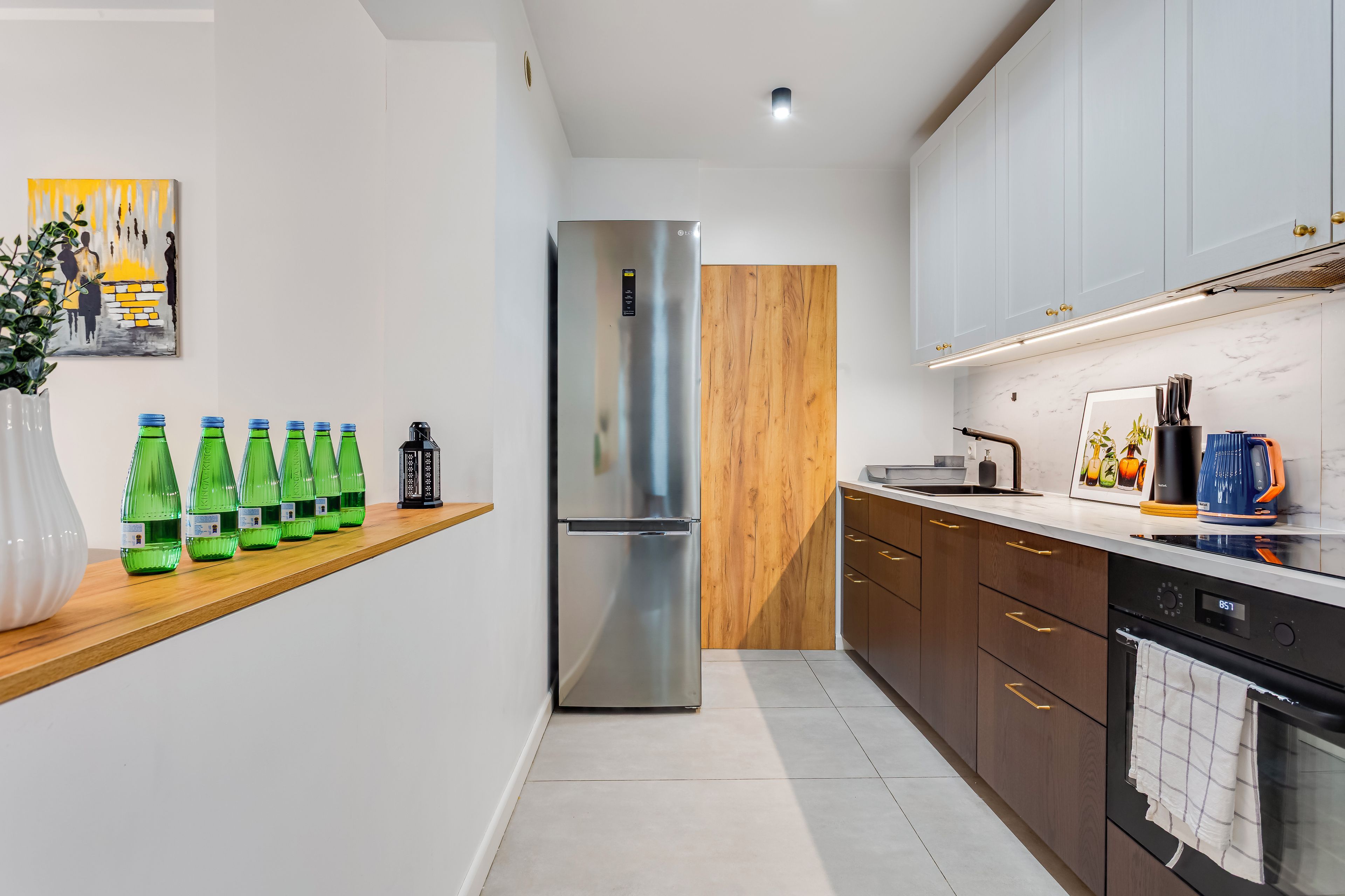 Una cocina moderna con refrigerador de acero inoxidable, armarios de madera y encimera de mármol.