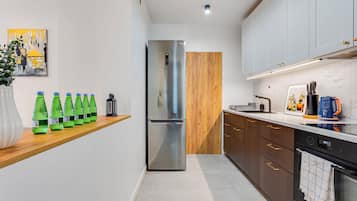 Una cocina moderna con refrigerador de acero inoxidable, armarios de madera y encimera de mármol.