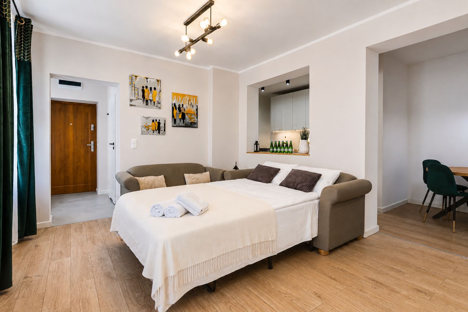 Un dormitorio moderno con cama, sofá, escritorio y obras de arte en las paredes.