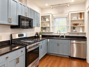 A modern kitchen with light blue cabinets, stainless steel appliances, and a wooden floor. - Crimson Cottage | 1.4 Miles to Bryant-Denny! (Tuscaloosa)