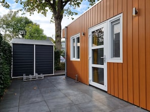 Ein modernes Gebäude mit Holzfassade, einer Garage und einer gepflasterten Terrasse.
