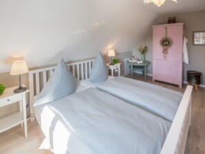 A bedroom with a bed, bedside tables, a dresser, and a small table with a plant. - Holiday Home in Dornum With Barbecue (Dornum)