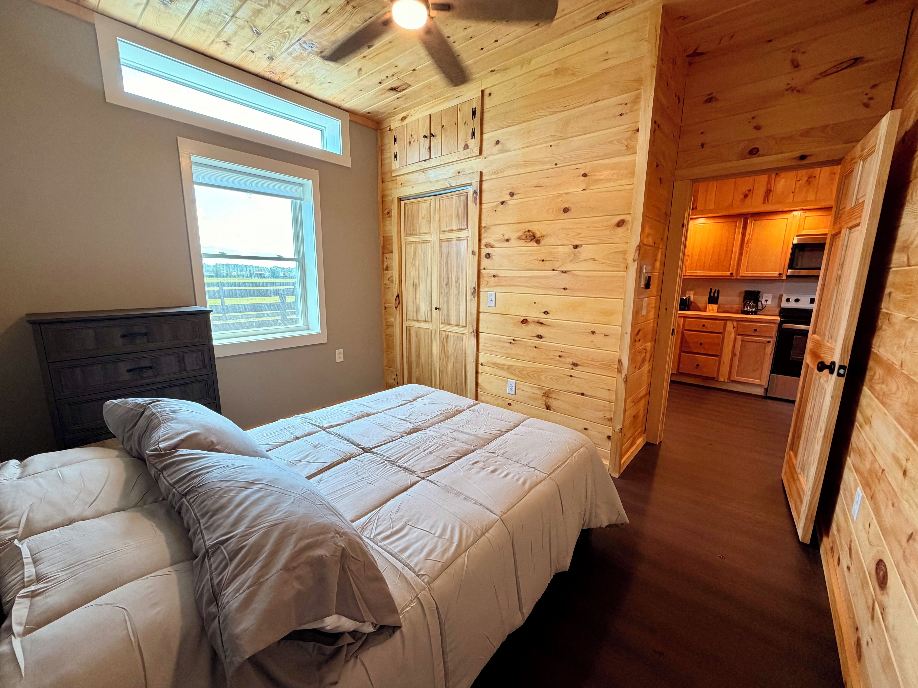 Un dormitorio con cama, ventana y vista a la cocina.