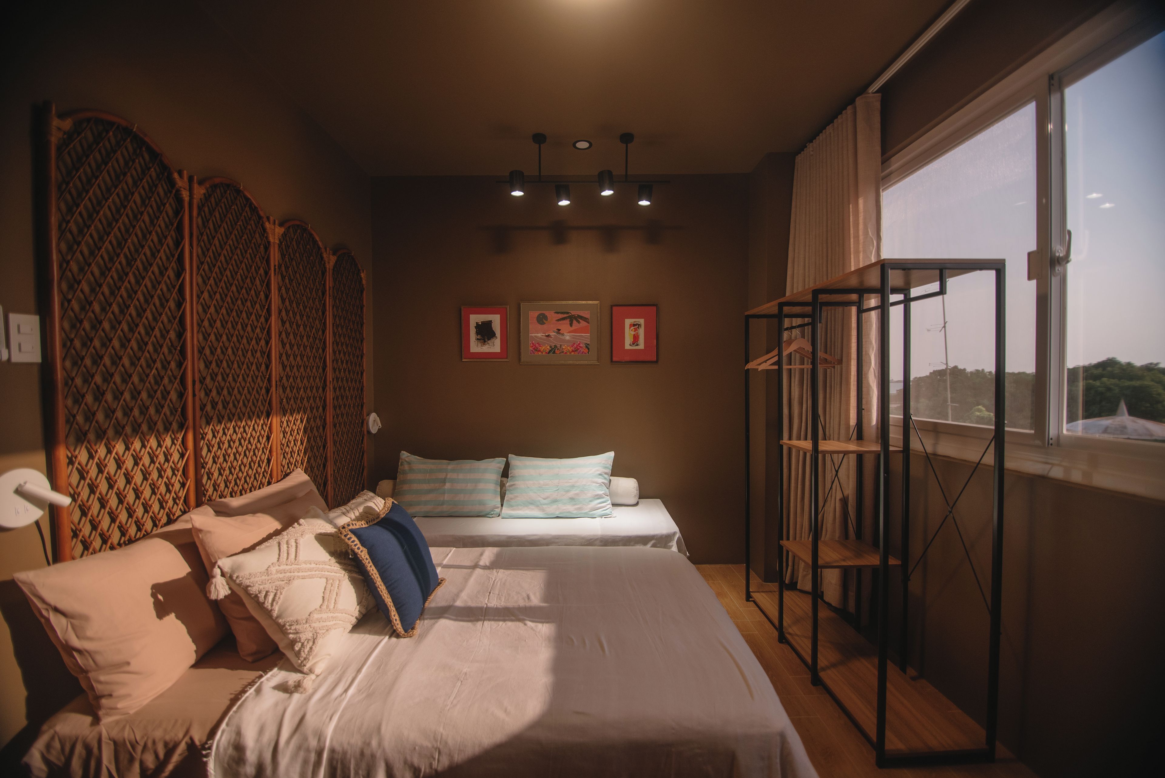 A bedroom with two beds, a window with a view, and artwork on the wall.