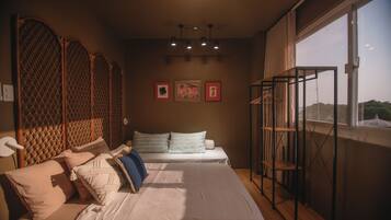 A bedroom with two beds, a window with a view, and artwork on the wall.