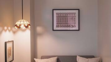 Un rincón acogedor con un banco acolchado, una lámpara decorativa y una obra de arte enmarcada en la pared.