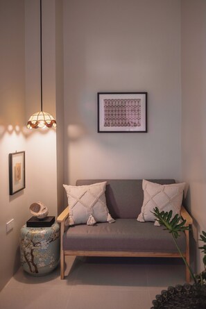 Un rincón acogedor con un banco acolchado, una lámpara decorativa y una obra de arte enmarcada en la pared.