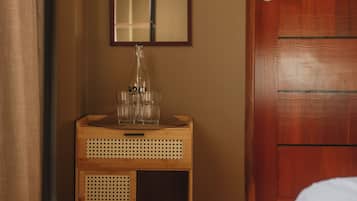 Un tocador de madera con espejo, una botella y vasos.