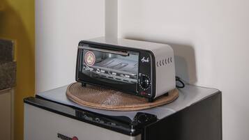 A kitchen area with a toaster on a stand, a framed black and white photograph on the wall, and a yellow wall.