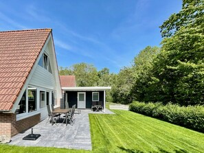 A two-story house with a patio, a dining area, and a lawn. - Holiday Home With 3 Bedrooms (Oostkapelle)