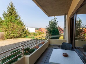 A balcony with a table and chairs, a railing, and a view of houses and trees. - Holiday Apartment With 1 Bedroom (Braunlage)