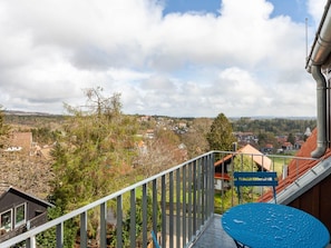 Ein Balkon mit Blick auf eine Stadt, einem blauen Tisch und einem Metallgeländer.