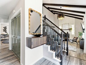 A staircase with black railings and a modern light fixture. - Jungle Oasis - Pool + Hot Tub + Game Rooms (Richardson)