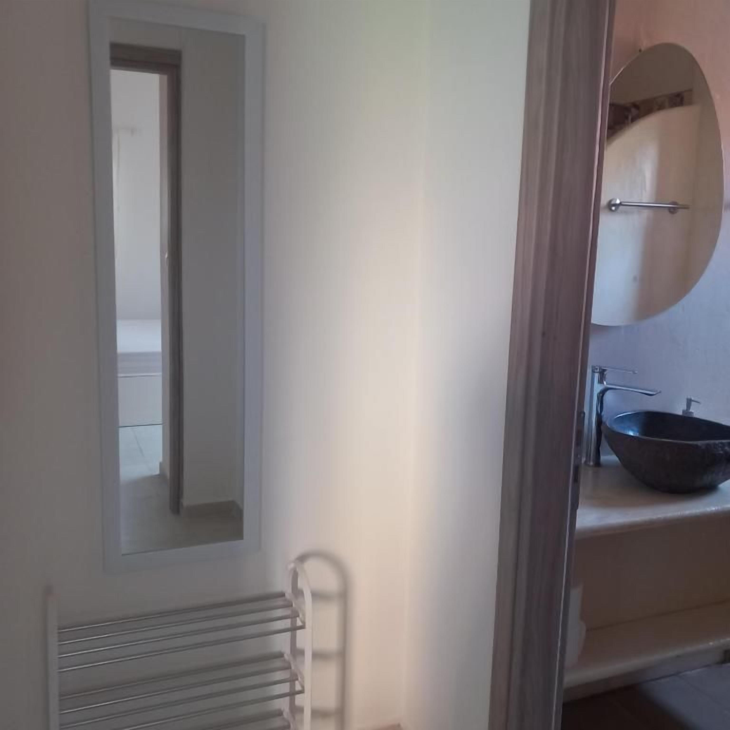 A bathroom with a mirror, a towel rack, and a sink with a basin.