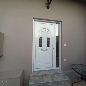 A white door with a glass panel, a small step leading up to it, and a wall-mounted light fixture above. - Yard House 284 Kalamata (Kalamata)
