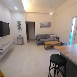 A modern living room with a flat-screen TV, a sofa, a coffee table, and a bar area. - Yard House 284 Kalamata (Kalamata)