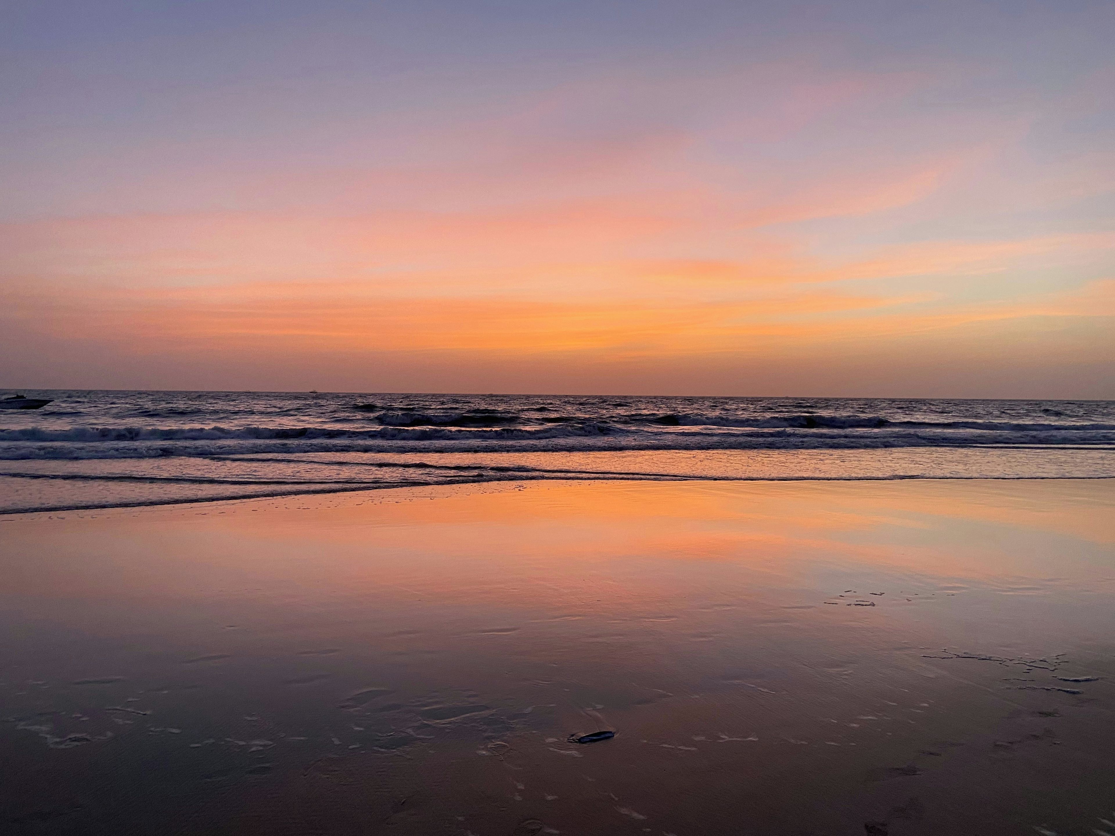 A beach with waves and a sunset.