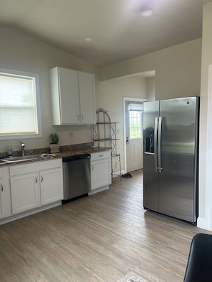 A kitchen with white cabinets, a stainless steel refrigerator, and a dishwasher.