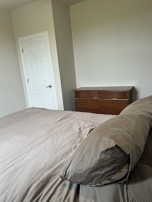 A bedroom with a bed, a dresser, and a door.