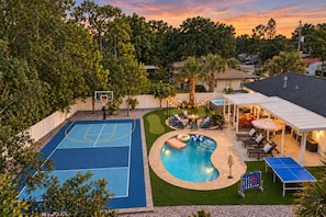 Ein Garten mit Basketballfeld, Schwimmbecken und Gartenmöbeln.