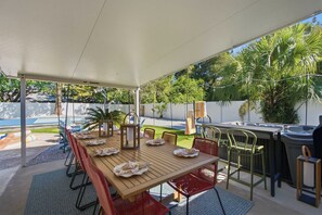 Een terras buiten met een houten eettafel, omringd door stoelen en een jacuzzi.