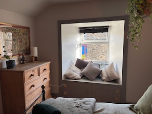 Ein Schlafzimmer mit integriertem Fensterbrett, einem Holzschrank und einem Bett mit grüner Decke.