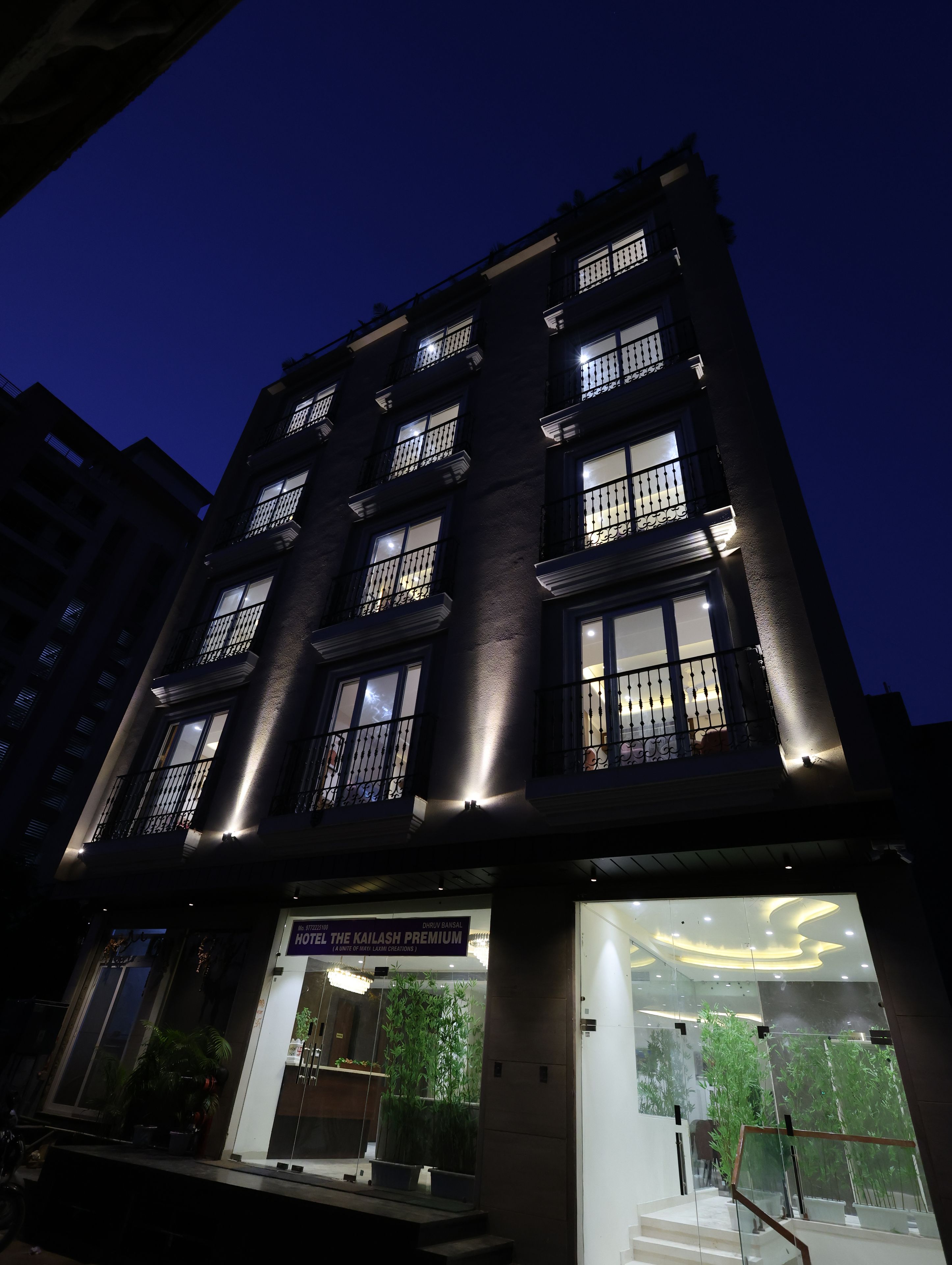 A multi-story hotel building with illuminated windows and a sign for 'HOTEL THE KAILASH PREMIUM.'