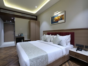 Una habitación de hotel con cama, mesita de noche y un cuadro en la pared.