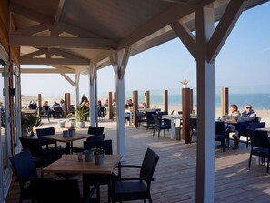 Eine Außenpatio mit Tischen und Stühlen mit Blick auf einen Strand.