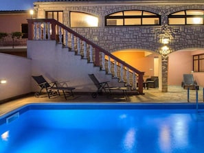 A pool area with a stone staircase leading to a second floor, a lounge chair, and a poolside table. - Dvori With Private Pool (Liznjan)