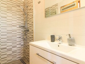 A modern bathroom with a shower, a sink, and a mirror. - Dvori With Private Pool (Liznjan)