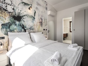A modern hotel room with a large bed, a wall mural, and a bathroom visible through an open door. - Casa Veritas With Pool (Visnjan)