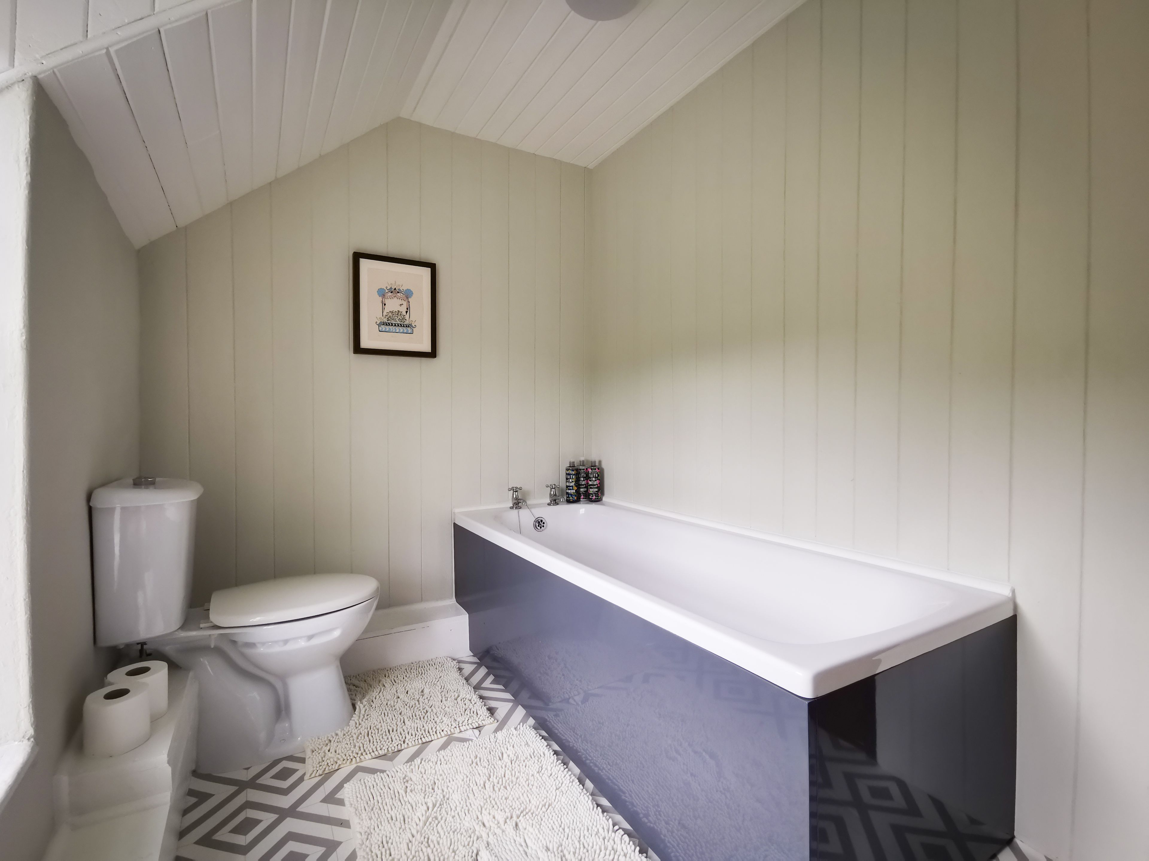 A bathroom with a toilet, a bathtub, and a patterned floor.