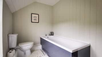 A bathroom with a toilet, a bathtub, and a patterned floor.