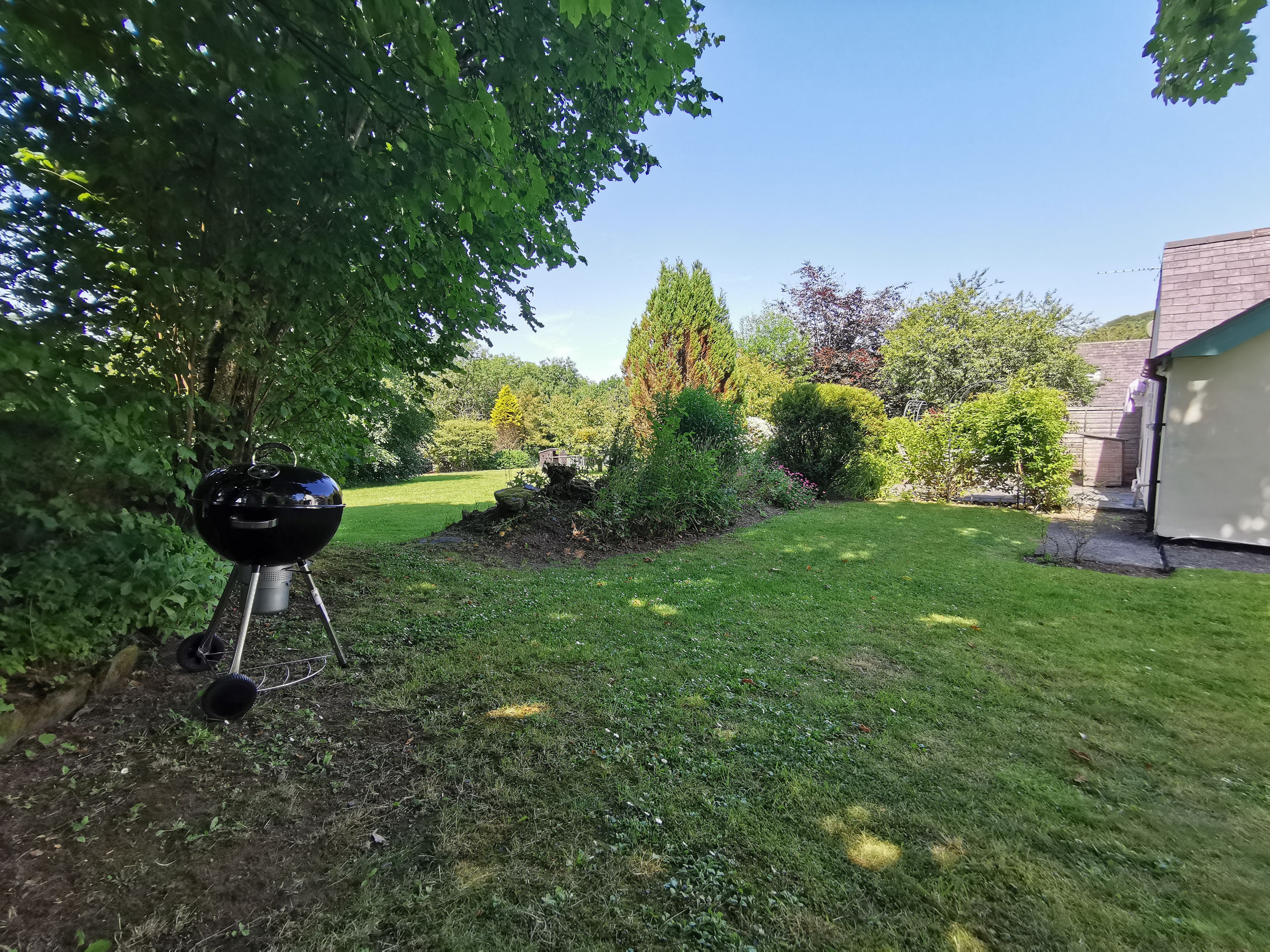 A backyard with a barbecue grill, a lawn, and a house.