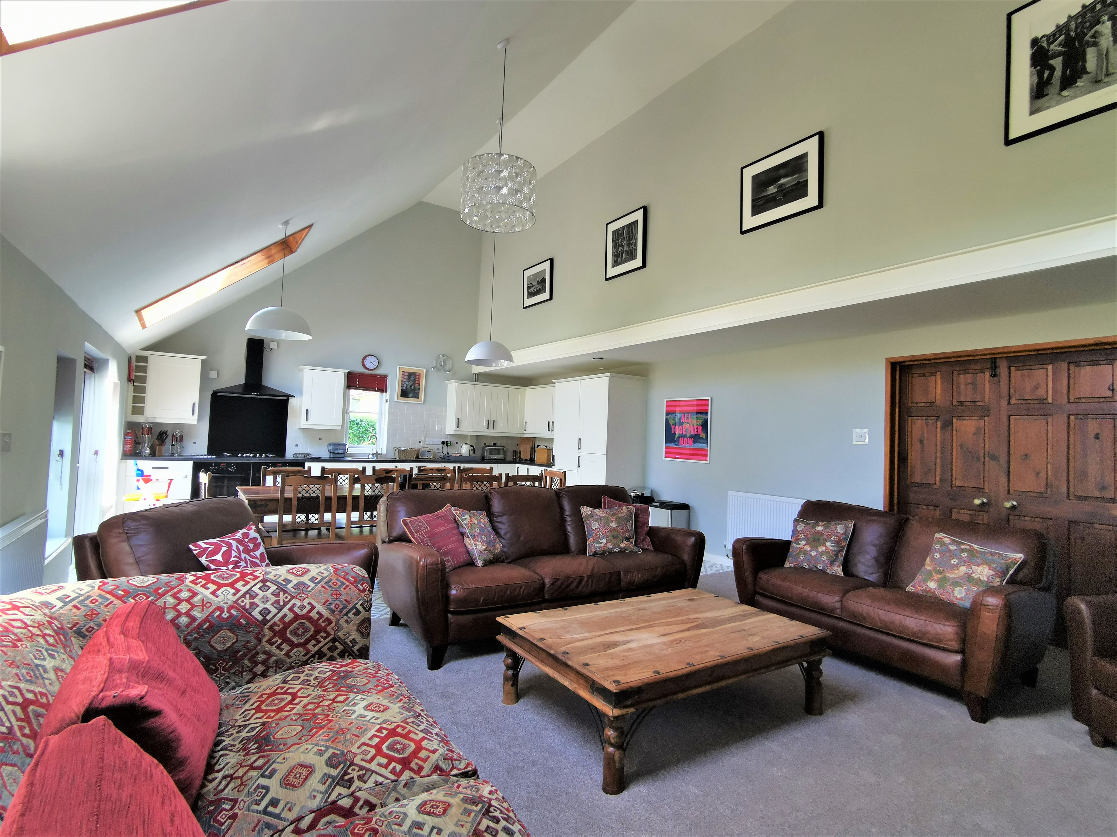 Uma sala de estar ampla, com lareira, sofás de couro e uma mesa de centro de madeira.