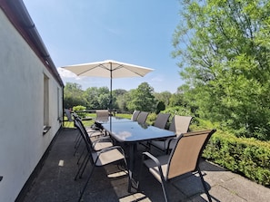An outdoor patio with a table and chairs, surrounded by greenery. - Wellstone Cottages  (Llanfyrnach)