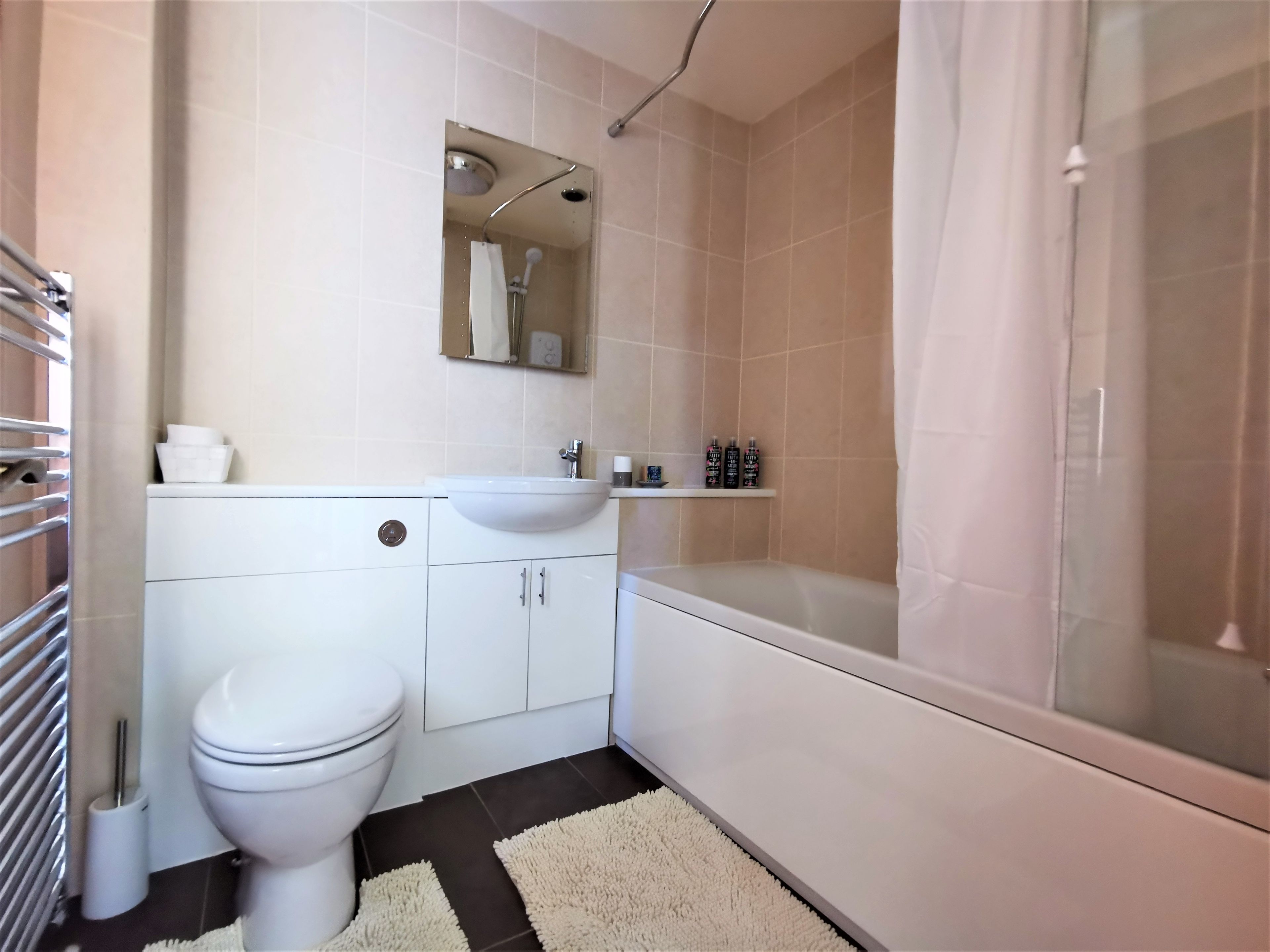 Un baño con inodoro, lavamanos, espejo, ducha y bañera.