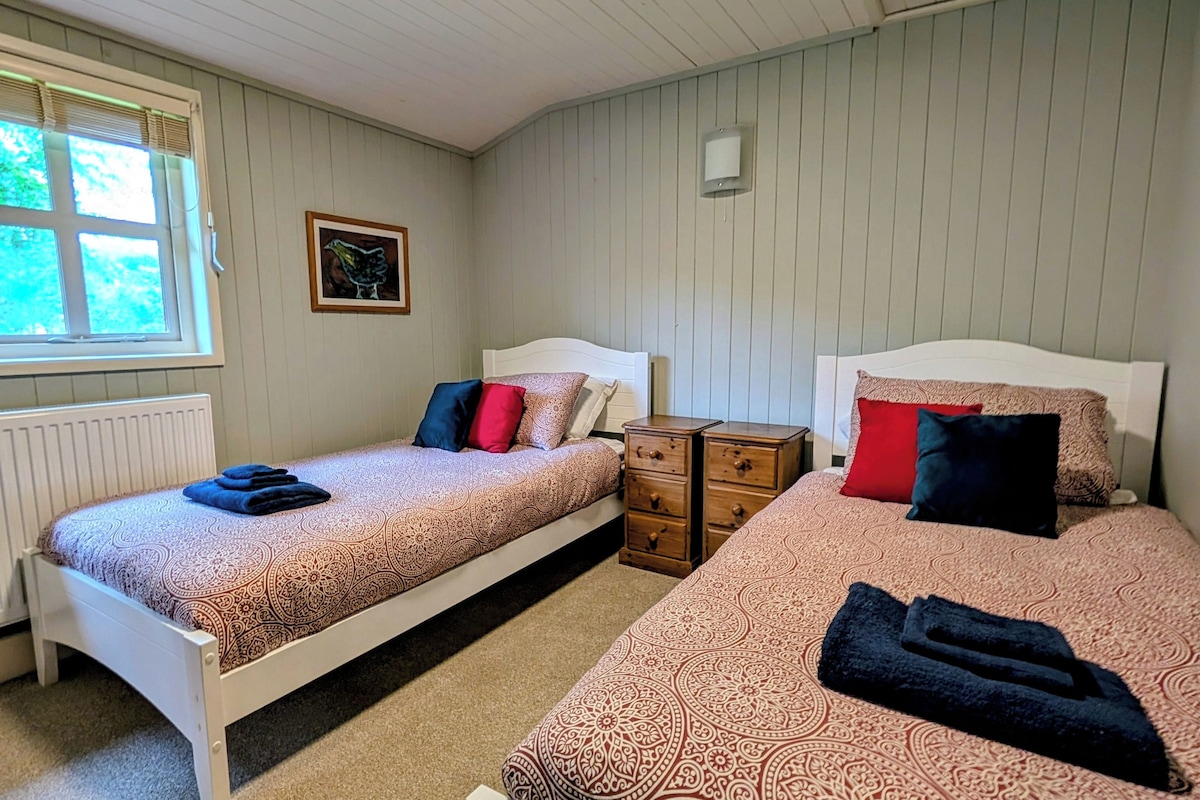Ein Zimmer mit zwei Betten, einem Fenster, einer Heizung und einer Wandleuchte.