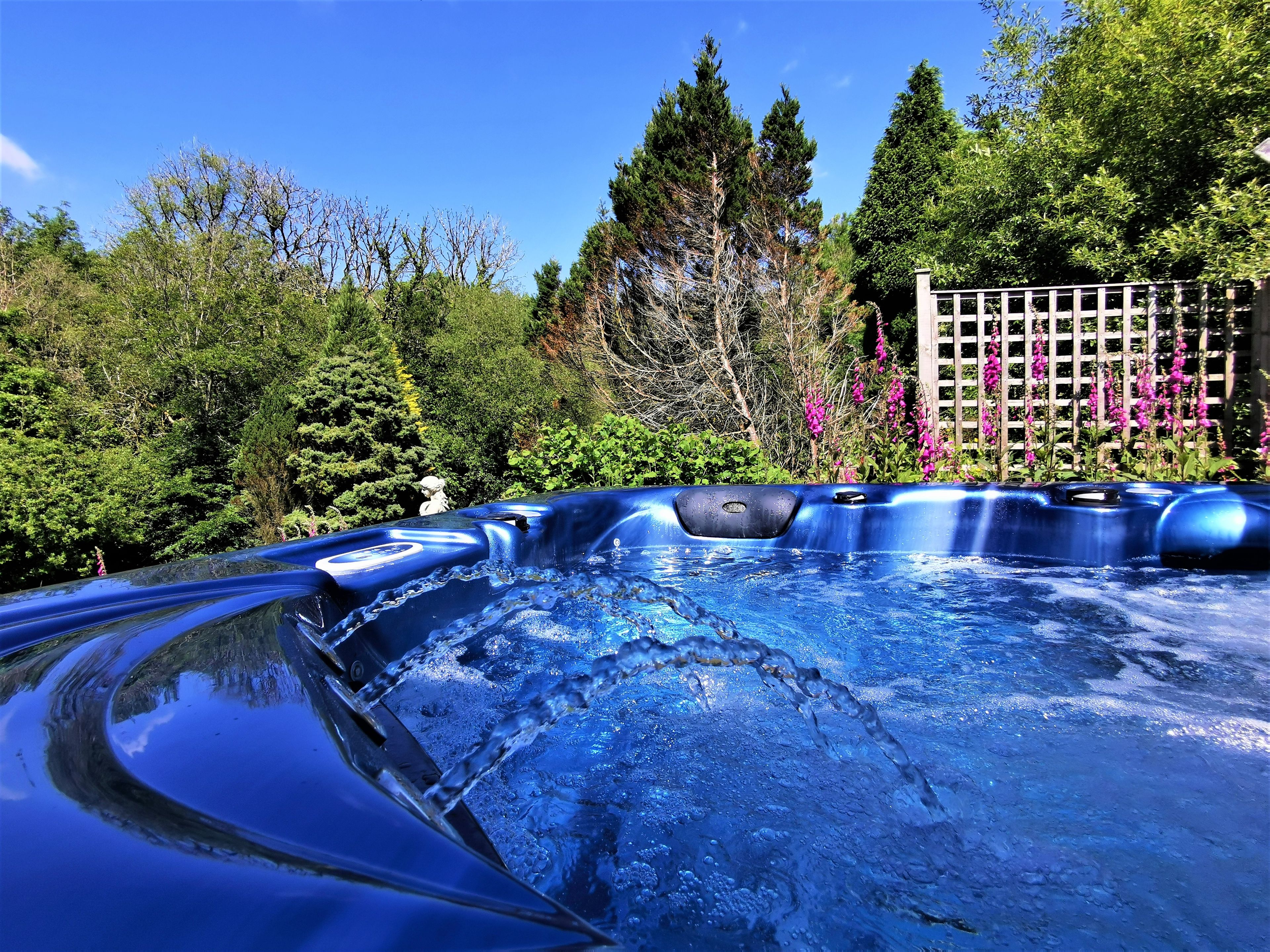 A hot tub surrounded by lush greenery and a wooden fence.